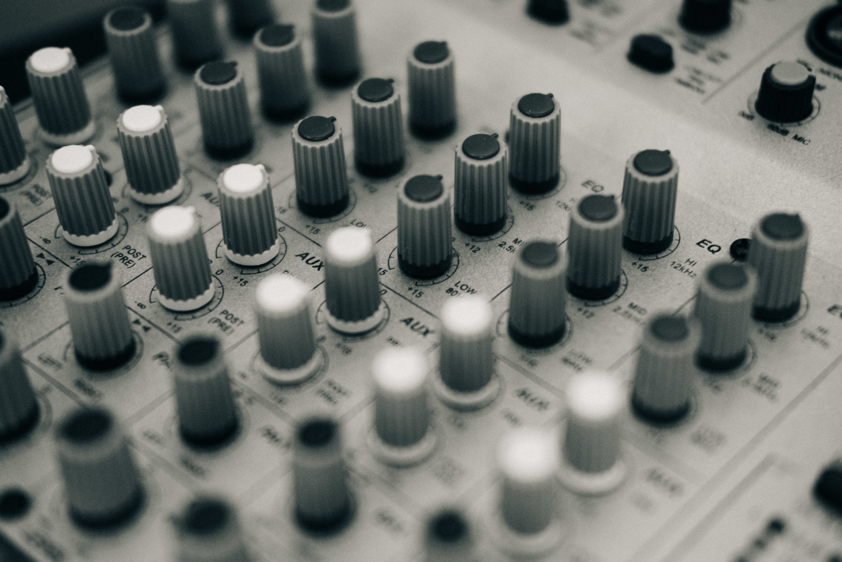 EQ knobs on audio mixing desk for film post-production, music production, game cinematics, commercials, short-form videos, trailers, podcasts.  Grey, white knobs for engineer to tweak the sonic spectrum in immersive, 3D, binaural, surround, stereo & mono.